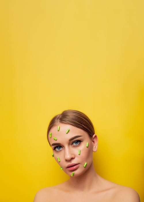 A Woman with Green Capsules on Her Face