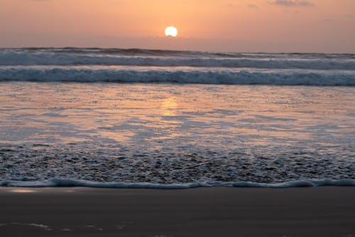 Scenic View of Ocean Waves Crashing on Shore during Sunset