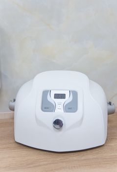 Close-up of a white electric face massager on a wooden surface, emphasizing skincare technology.