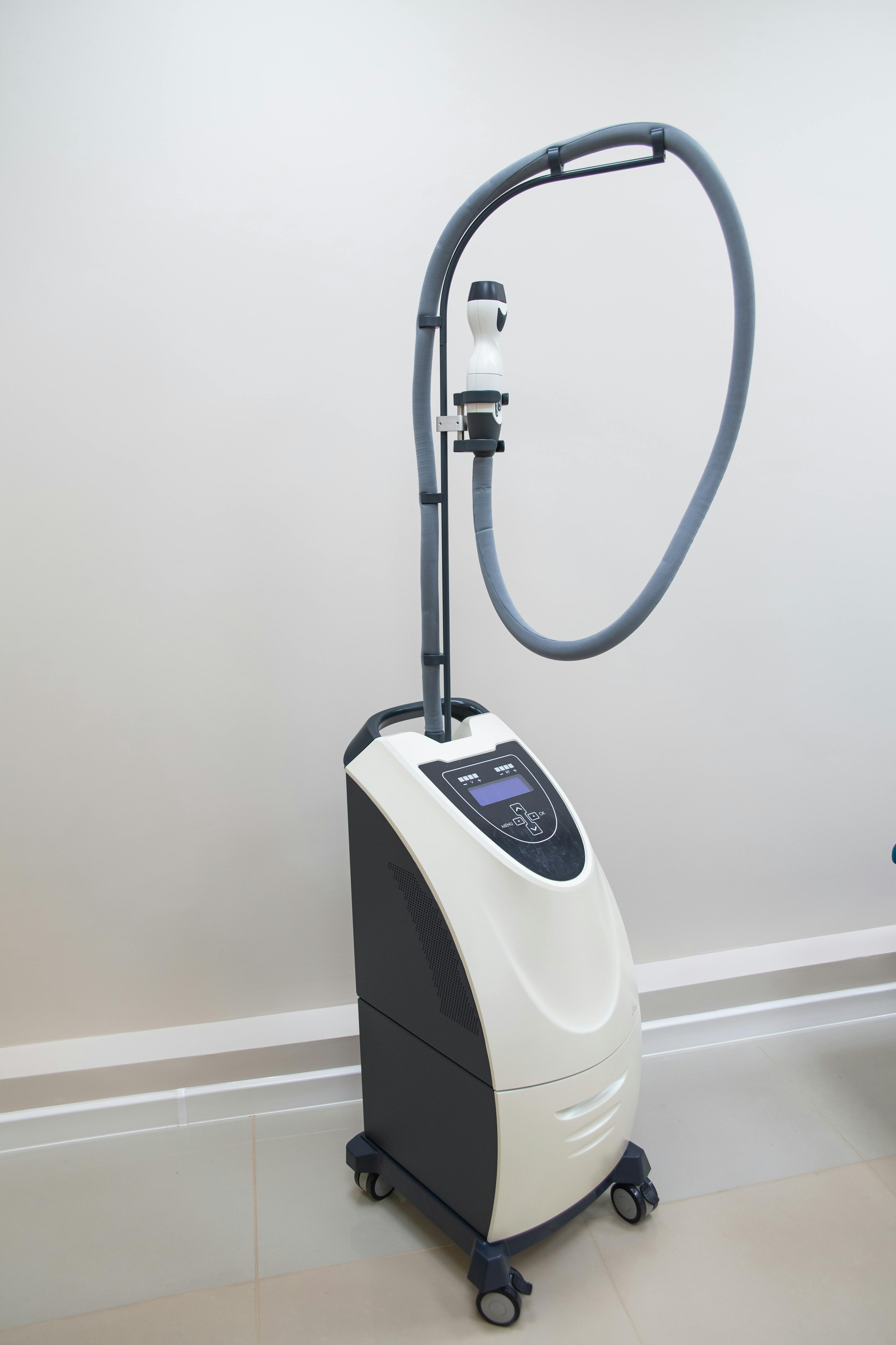 A sleek, modern medical laser device in a clinic environment ready for patient treatment.