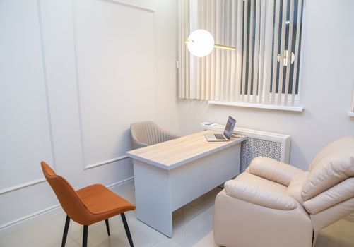 Stylish minimalist home office setup featuring a laptop on a desk with contemporary furniture.