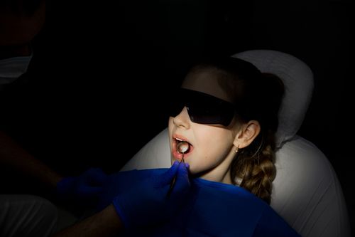 Free A dentist examines a young girl using medical instruments under protective eyewear. Stock Photo