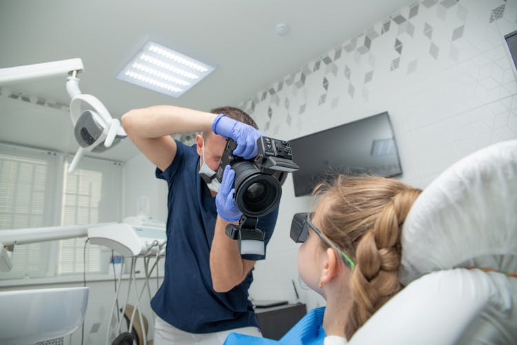 A Dentist Taking A Picture Of Teeth Of A Girl 