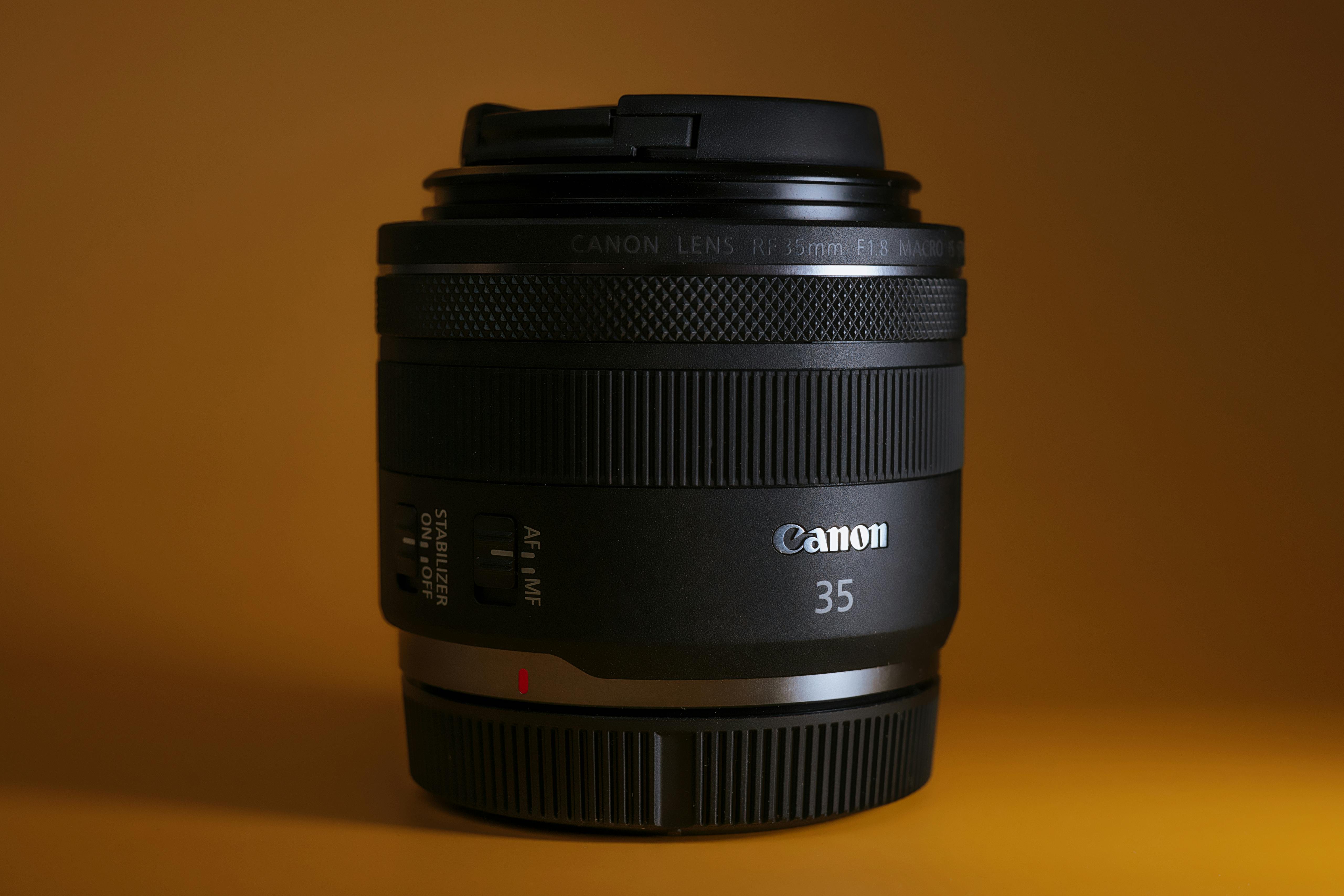 Free Detailed close-up of a camera lens with yellow background, showcasing lens specifications and design. Stock Photo