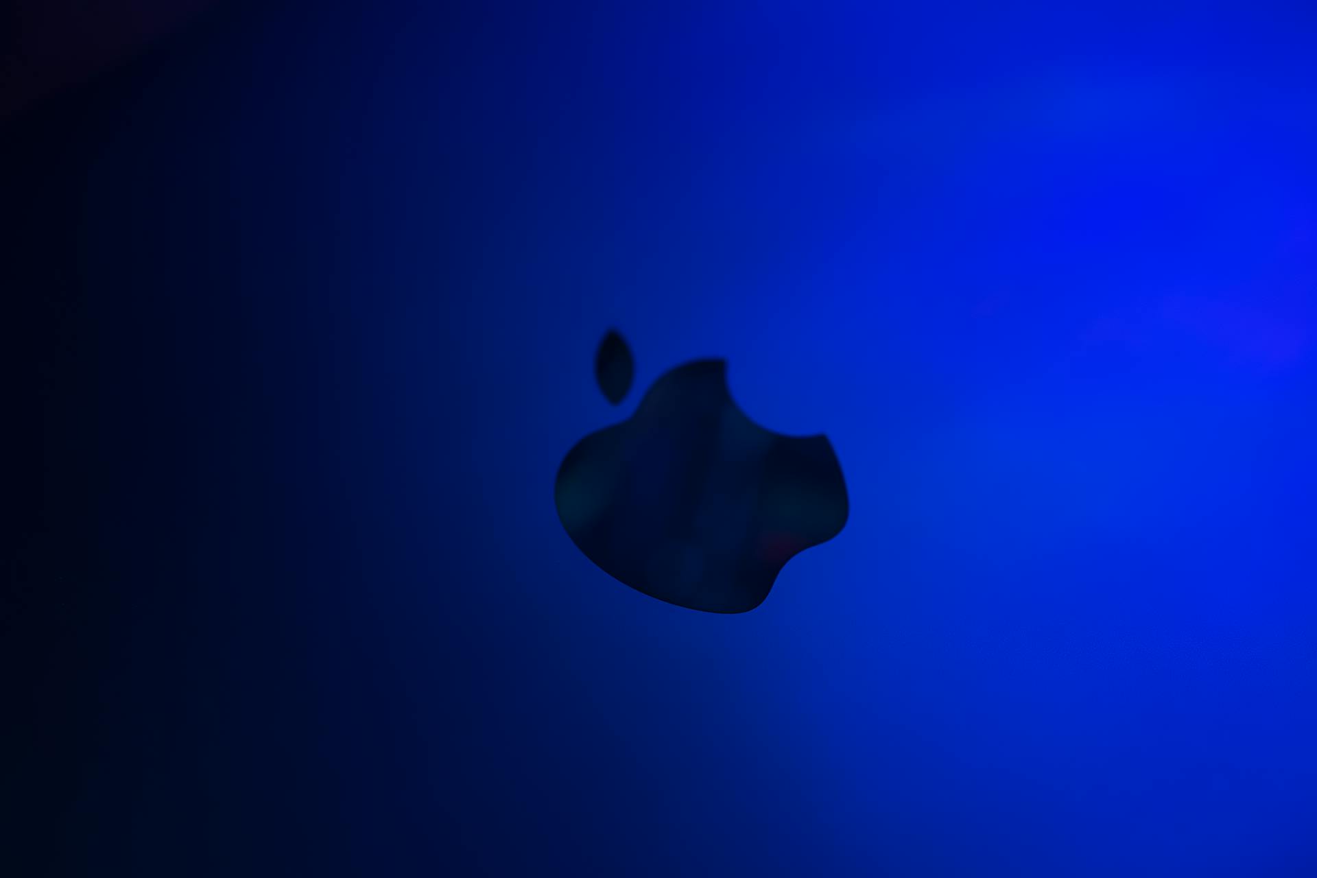 Silhouette of an apple logo against a blue gradient background, minimalistic design.