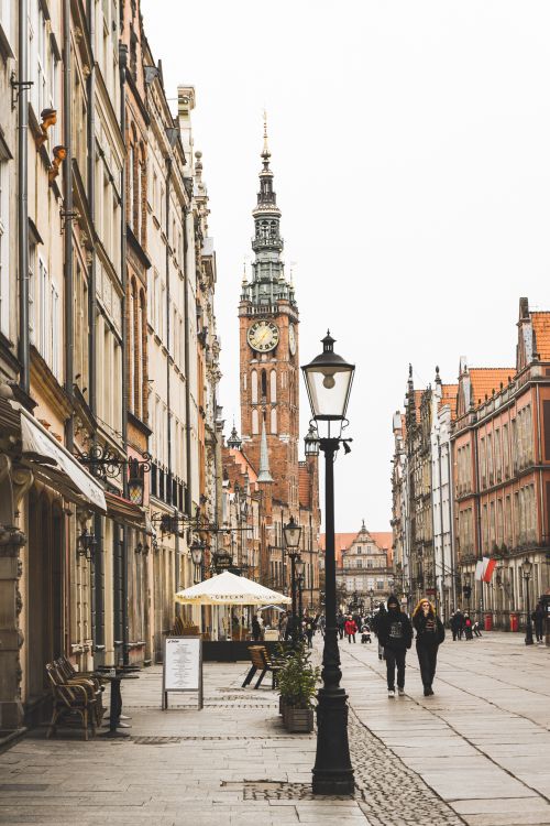 Free Explore the historical streets of Gdańsk, Poland with a view of the iconic clock tower and bustling pedestrians. Stock Photo