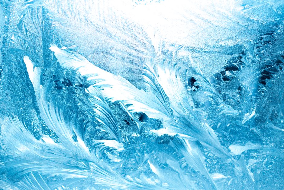Detailed close-up of intricate frosty ice patterns on a glass surface, capturing winter textures.