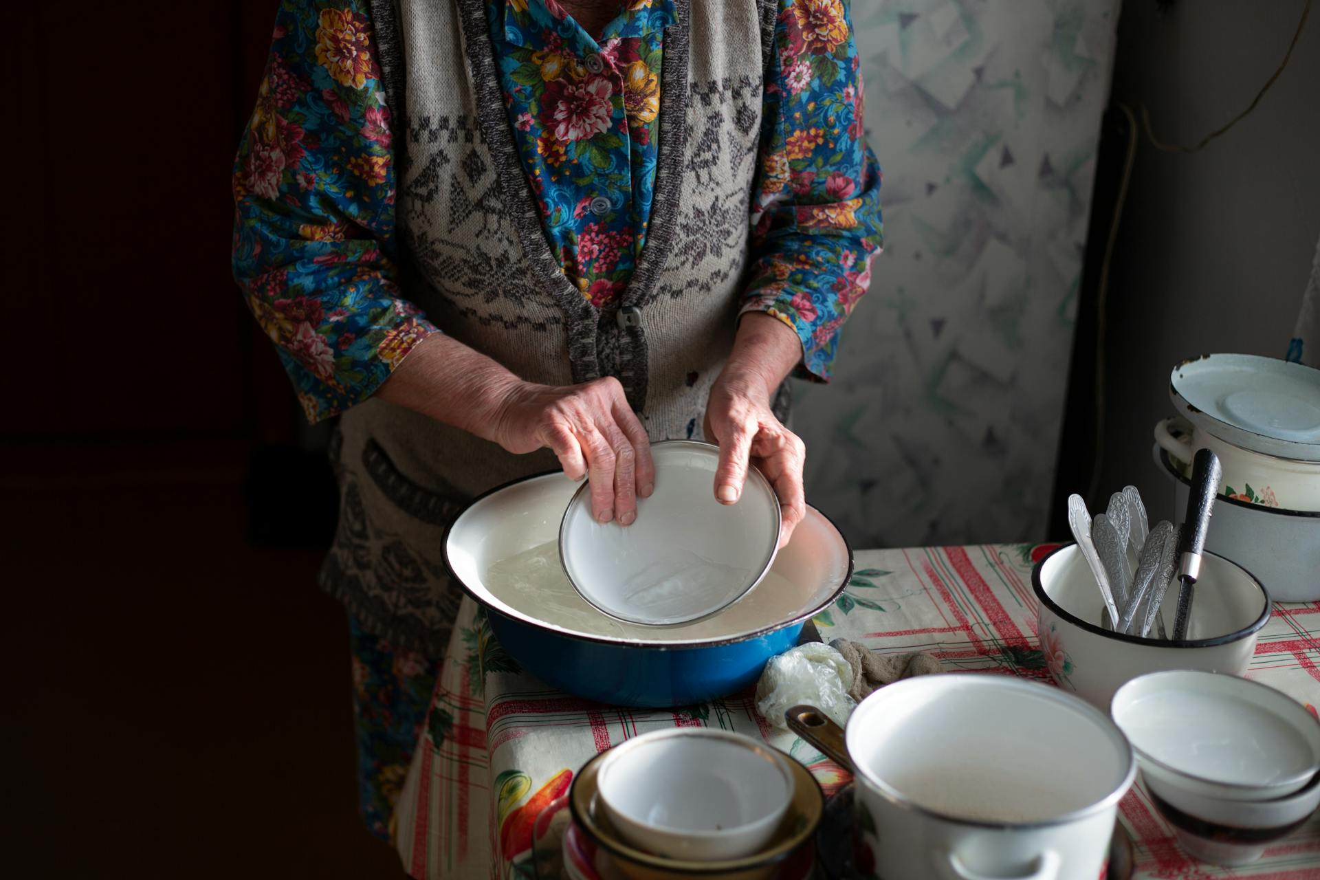 A Person Rinsing a Bowl with Water from a Stainless Steel Basin