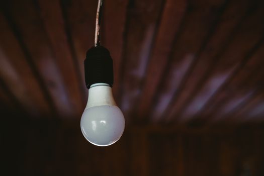 A close-up shot of a single light bulb hanging from a wooden ceiling, creating a rustic ambiance.