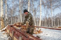Man Working With Wood in Forest on Winter Day