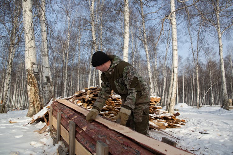 Man Piling Wood In The Forest In Winter 