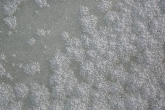 Detailed close-up of frosty ice texture on a surface during winter.