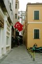 Turkish flag above pavement with urban buildings