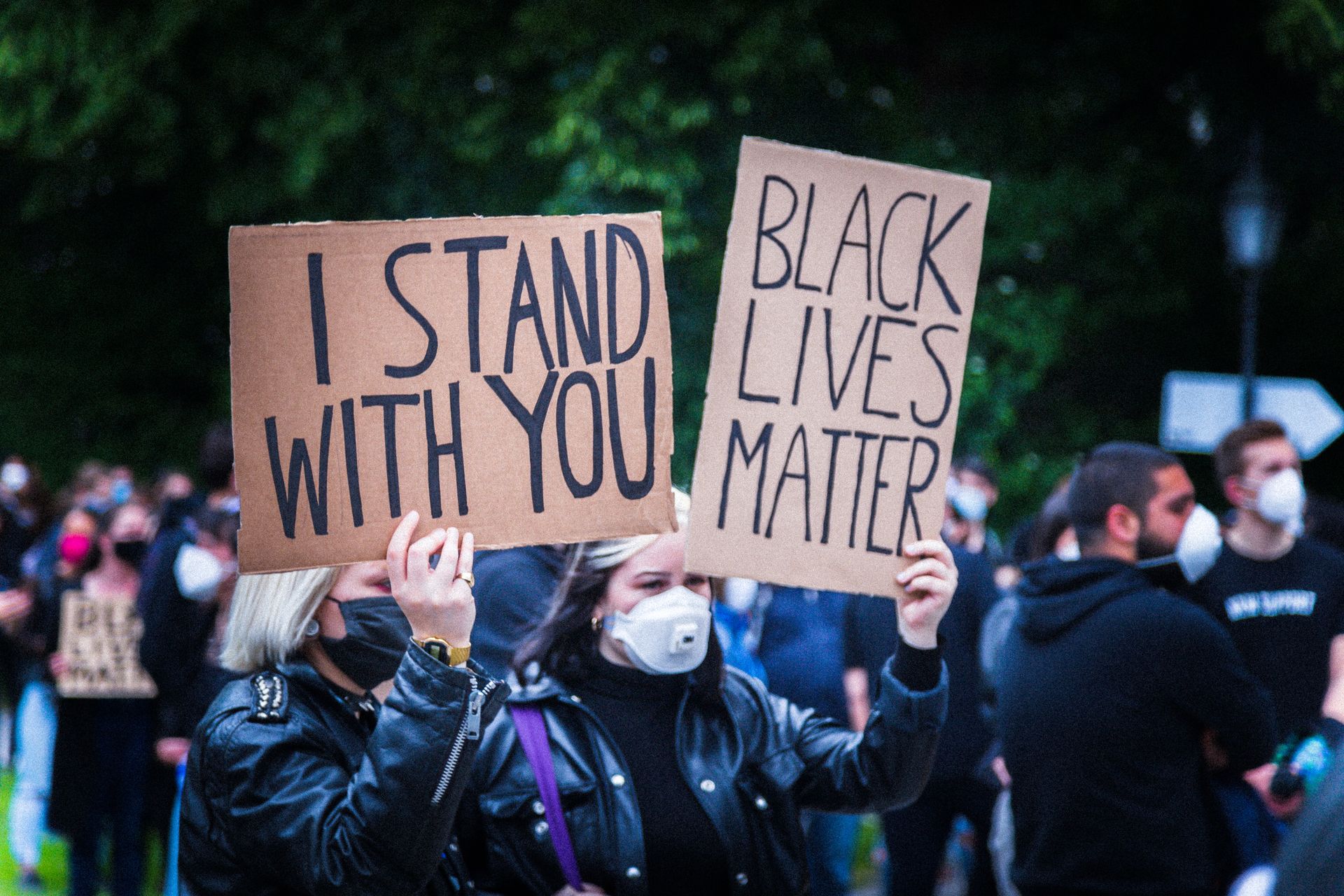 Protesters holding 'I Stand With You' and 'Black Lives Matter' signs at a rally.