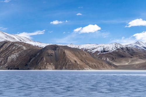 Free Beautiful snow-capped mountains with a frozen lake under a clear blue sky. Stock Photo