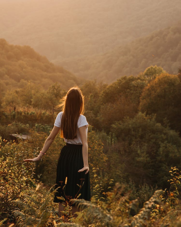 Woman Standing On Grassy Hill