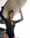 Female carrying surfboard on head on seashore