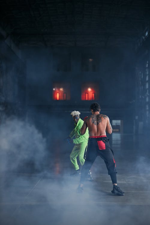 A Pair of Men in Costumes Acting on a Fighting Scene