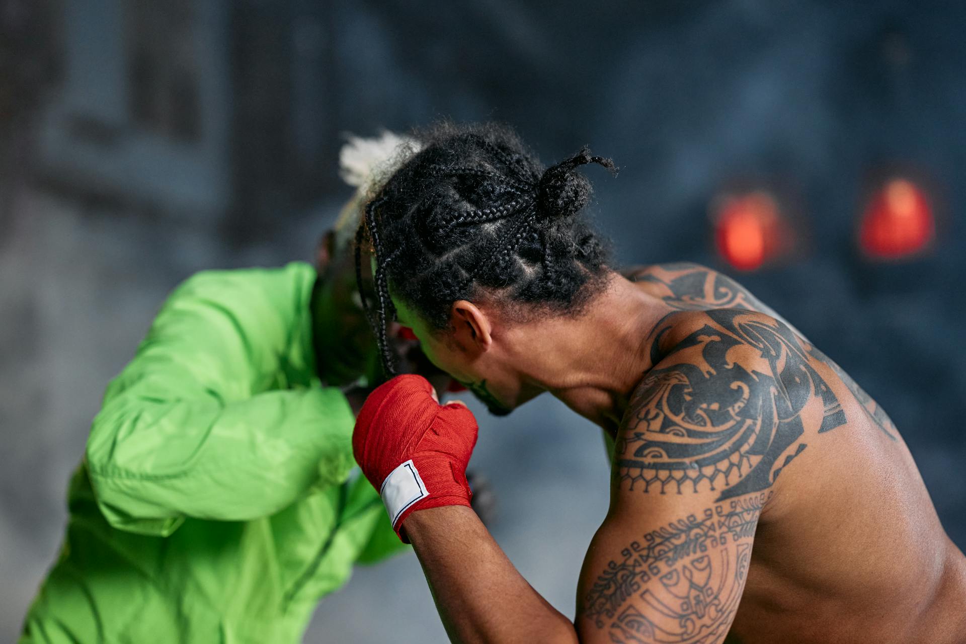 A Man in Green Fighting a Tattooed Man Without a Shirt