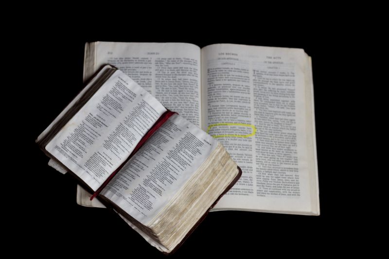 Biblia abierta sobre otra Biblia en fondo oscuro