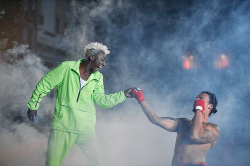 Free Two men engage in a playful boxing scene surrounded by smoke indoors. Stock Photo