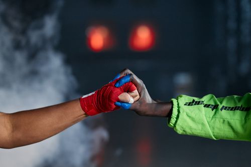 Free Close-up of two wrapped hands in a fist bump amid smoke, symbolizing unity in martial arts. Stock Photo