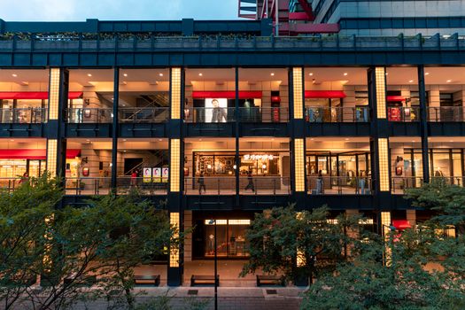 Illuminated modern shopping mall in Taipei with vibrant storefronts and urban architecture visible at dusk.