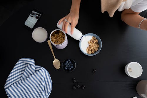 Person Pouring Milk on Bowl of Cereal