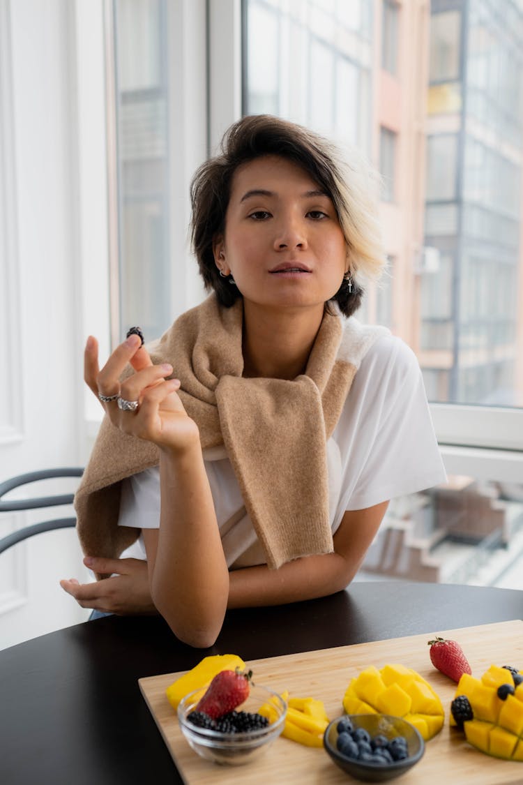 Woman Eating Fruits From Wooden Chopping Board