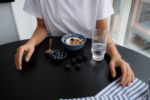 A healthy breakfast of granola with blueberries and blackberries, served with water.