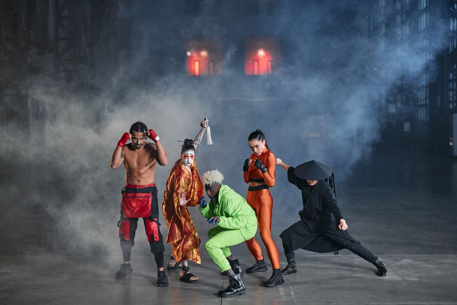 Dynamic group of diverse cosplayers striking action poses in an atmospheric indoor setting with smoke.
