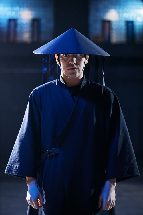 Free Man in an Asian warrior costume with a triangular hat in a studio setting. Stock Photo