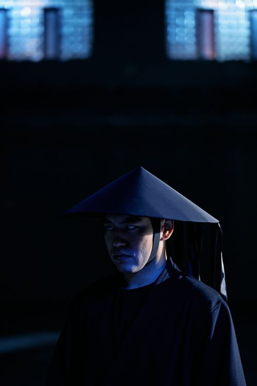Free Cosplayer dressed as a dark-themed game character with a ninja hat, captured in moody lighting. Stock Photo