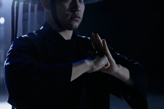 Cosplay enthusiast dressed as Raiden practicing martial arts poses in a studio setting.