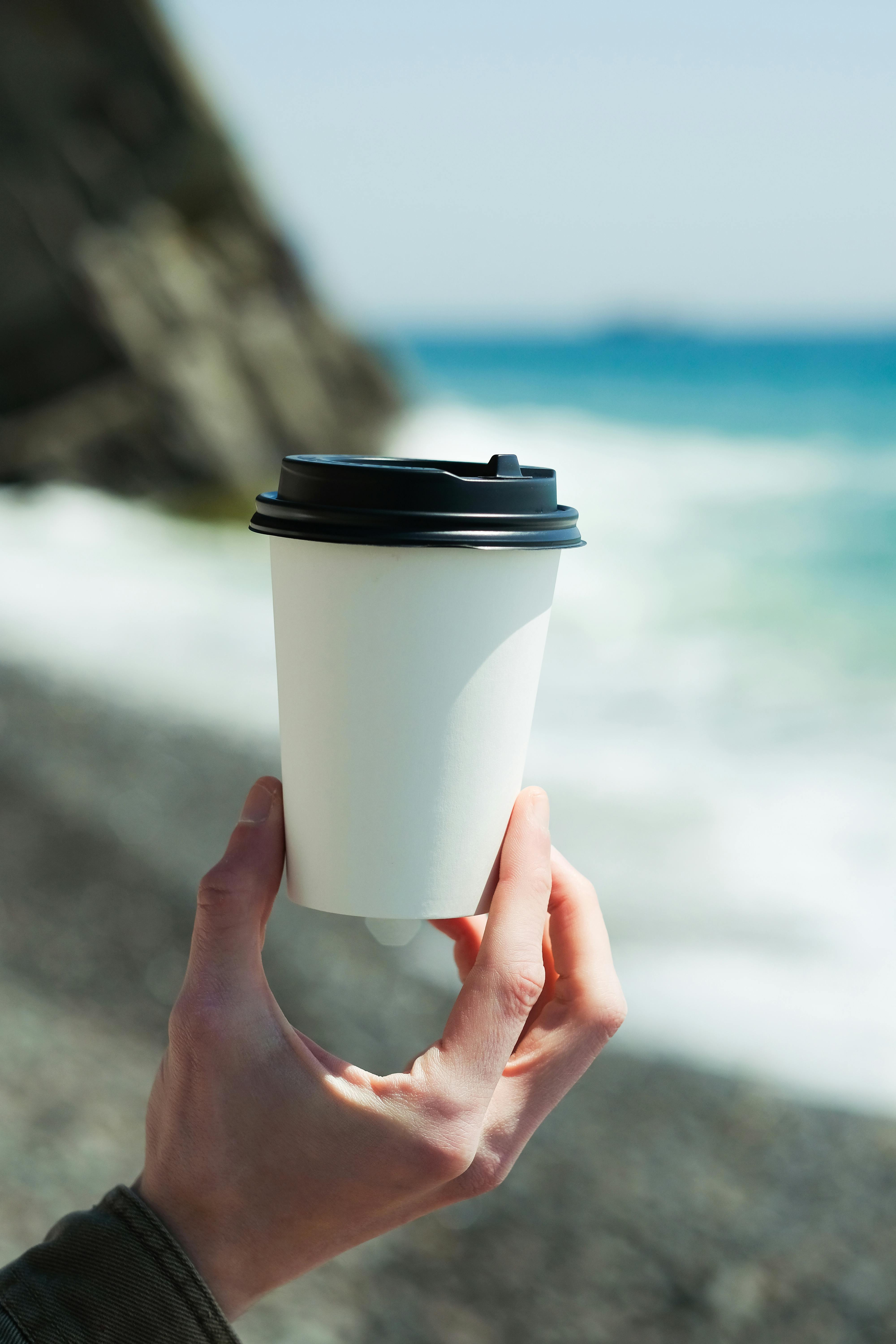 Cardboard - paper cup of coffee placed on the stones of a jetty in