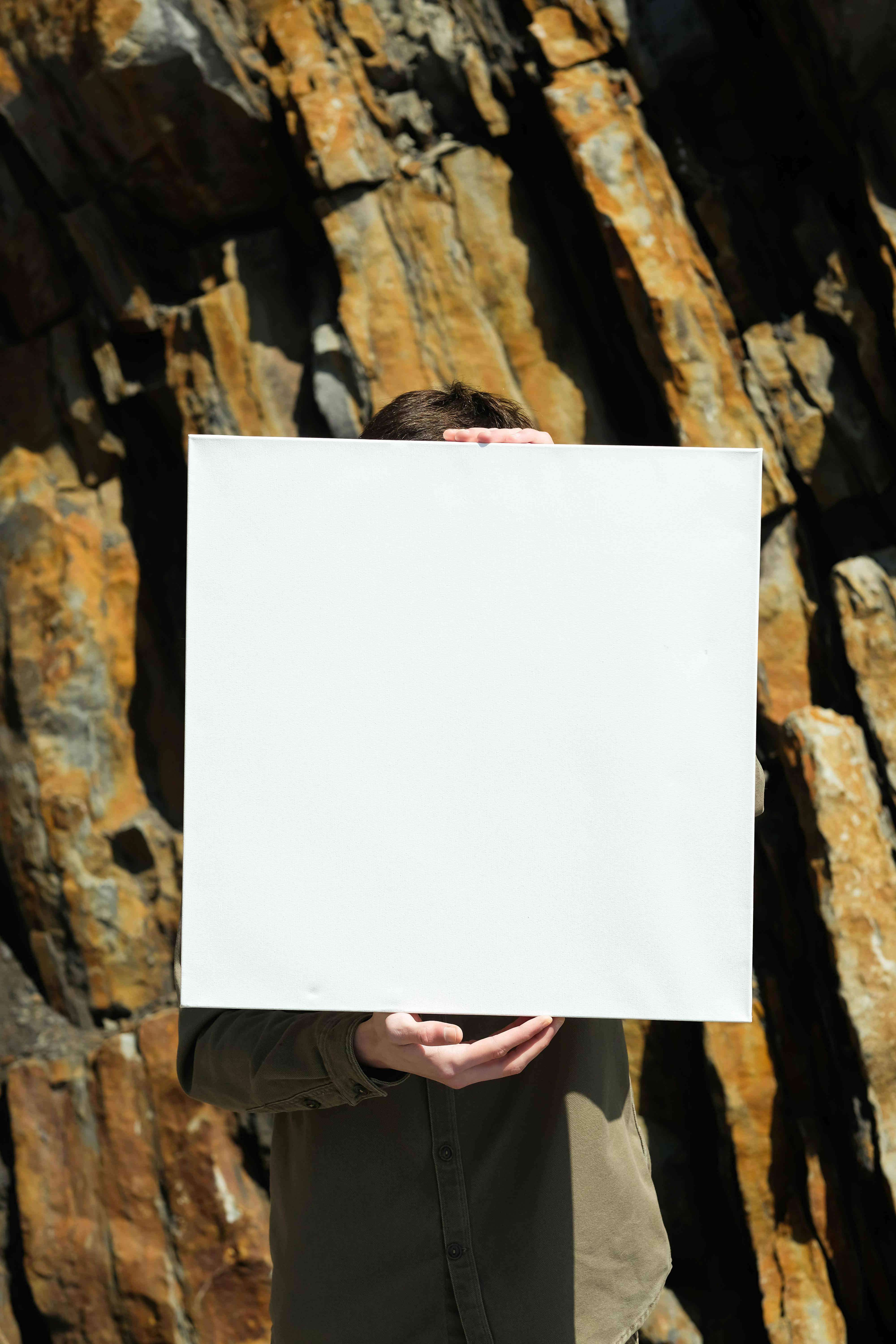 Man Holding a Blank Canvas in Front of Him Free Stock Photo