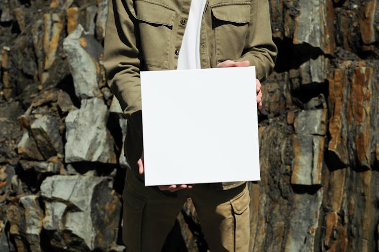 Person In Khaki Clothes Holding White Square Box