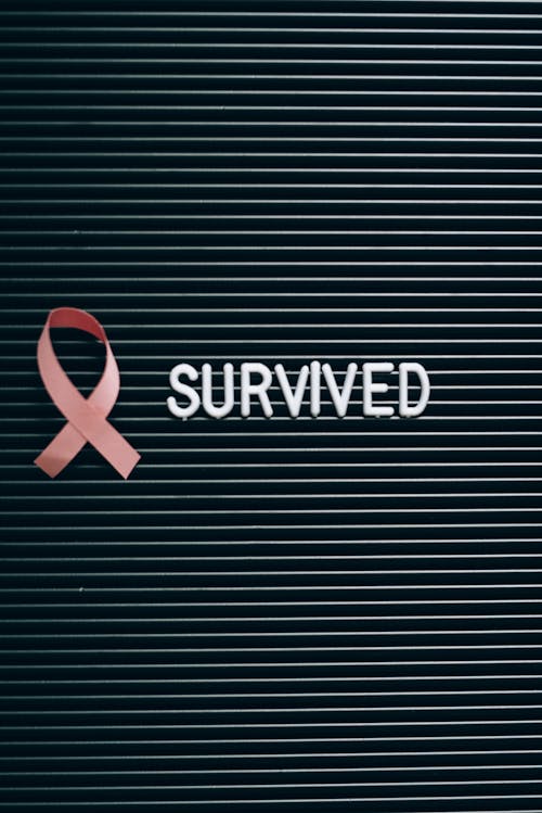 Free A Pink Ribbon beside a Survived Note on a Letter Board Stock Photo