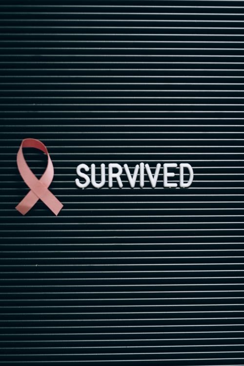 Free Pink ribbon and 'SURVIVED' note symbolizing breast cancer awareness. Stock Photo