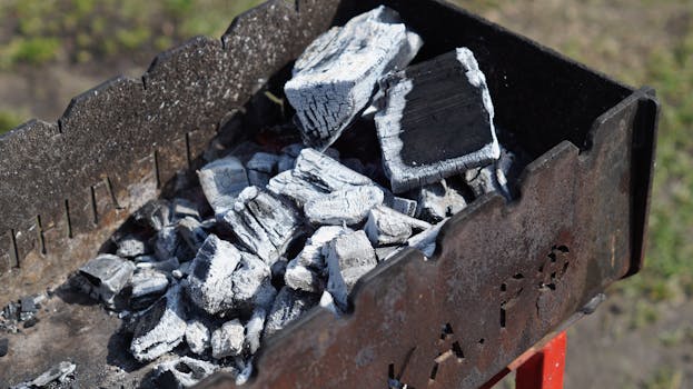 A detailed close-up of charred coals in an outdoor grill, showcasing high heat and barbecue readiness.
