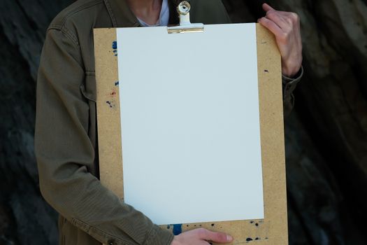Close-up of a person holding a blank clipboard, ideal for design mockups and presentations.