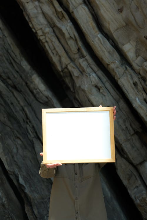 Man Holding a Blank Piece of Paper in a Picture Frame in Front of Him 
