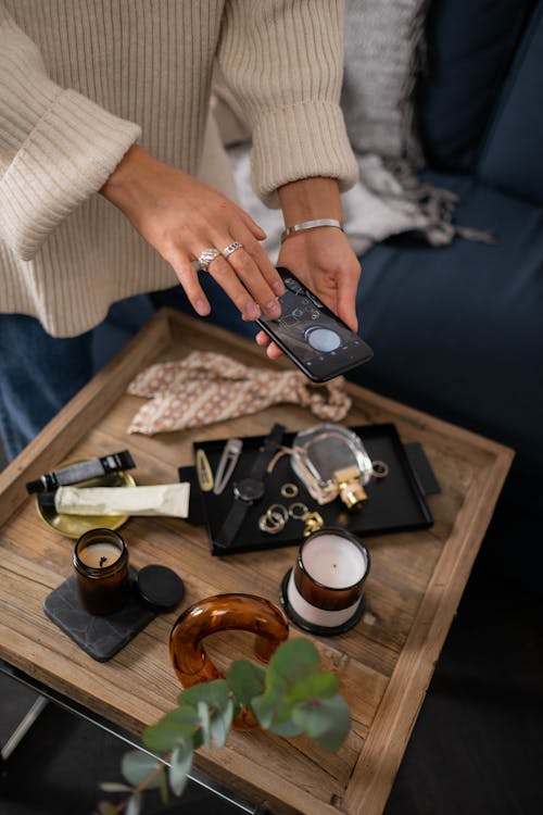 Person Taking Photo of Perfume and Accessories on a Wooden Tray 