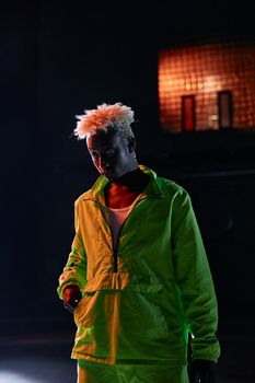 Person with afro hair stands in a dark room illuminated by neon green light, creating a moody atmosphere.