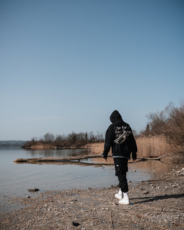 A Man in Black Hoodie Walking Near the Lake