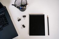 Black Notepad beside a Black Pencil