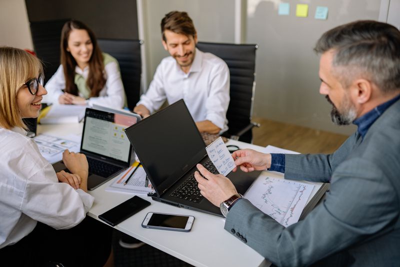 HR manager and team reviewing employee records and leave approvals on a laptop in a modern office