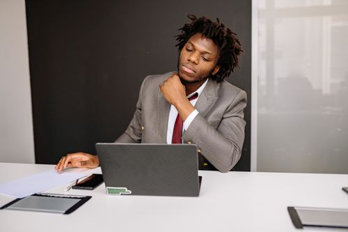Free Focused businessman working at desk with laptop and documents in modern office Stock Photo