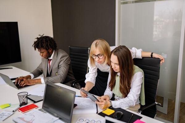 Three colleagues at screens in a meeting room