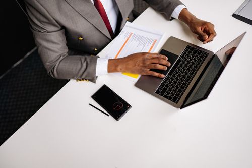 Free A business professional wearing a gray suit working on a laptop in an office setting. Stock Photo